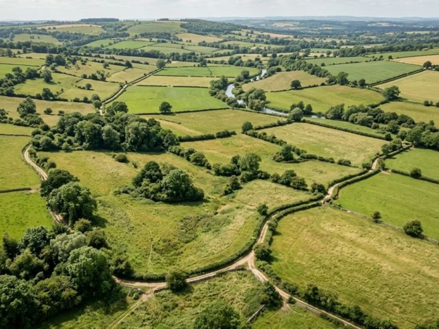 Возвышенный вид на несколько зеленых земельных участков без домов, доступных для покупки без подряда.